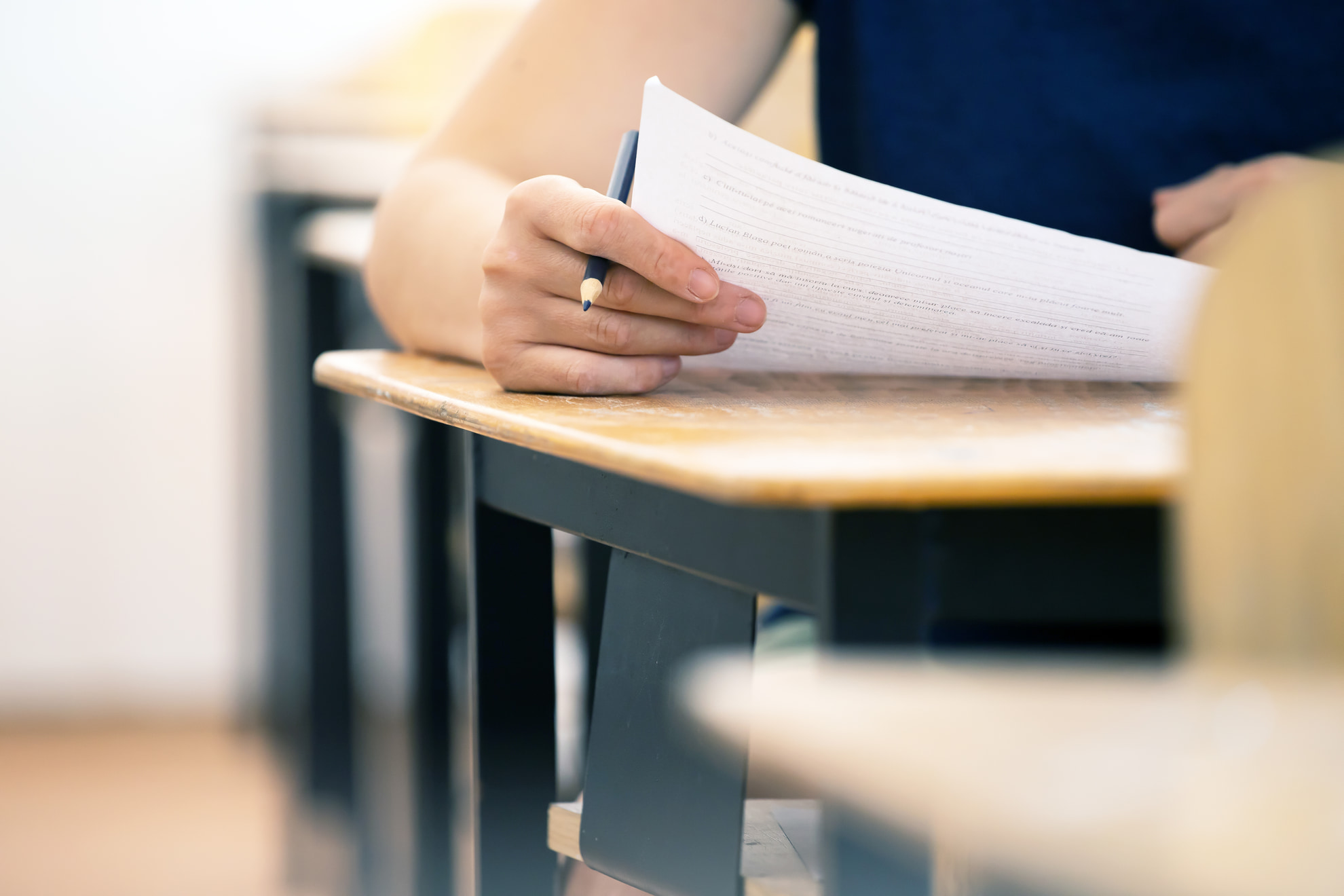 Student writing final exam in classroom. Student writing final exam in classroom.